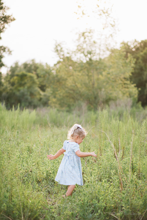Little girl twirls in sunlit field